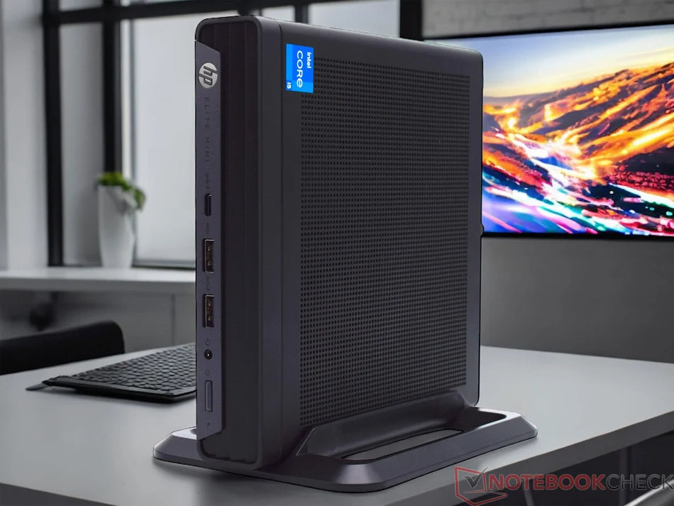 a black HP iCent mini desktop computer placed on a desk, with a large TV screen in the background.