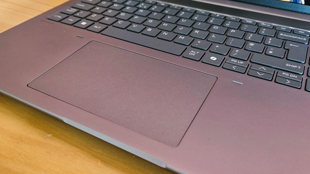 a close-up view of a laptop keyboard and a touchpad on a wooden surface.