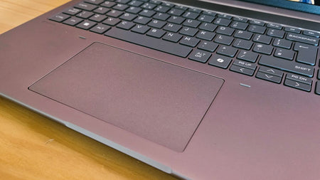 a close-up view of a laptop keyboard and a touchpad on a wooden surface.
