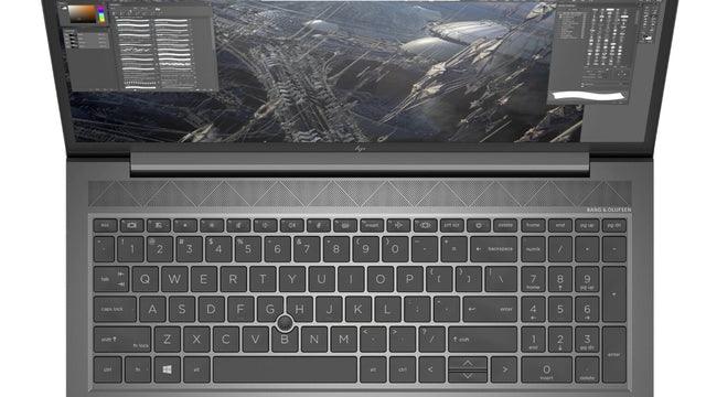a laptop with a large, detailed wallpaper displayed on the screen. The laptop has a black keyboard and a black and silver design on the front.
